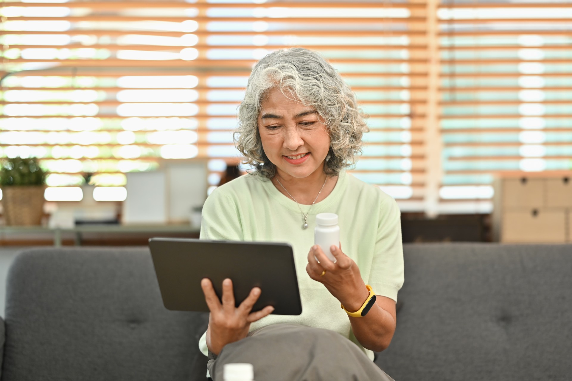 Mature woman holding tablet and discussing prescription medications with doctor on video call. Telehealth consultation concept.